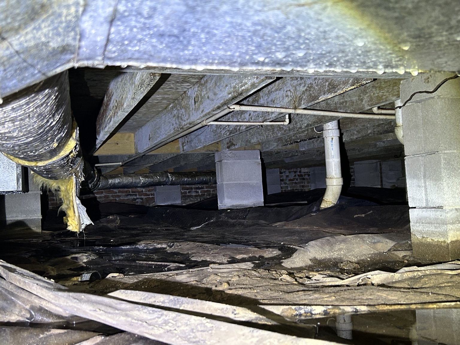 Flooded crawl space with standing water over the vapor barrier, wet floor joists and damaged ductwork